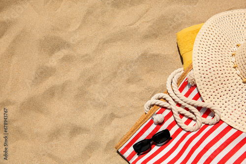 Fototapeta Naklejka Na Ścianę i Meble -  Striped beach bag, sunglasses, towel and hat on sand, flat lay. Space for text