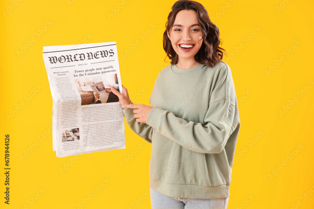 Young woman with newspaper on yellow background - obrazy, fototapety, plakaty 