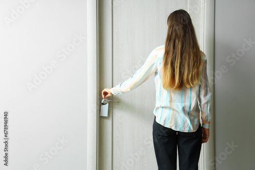 Woman with door hanger in hotel room, back view