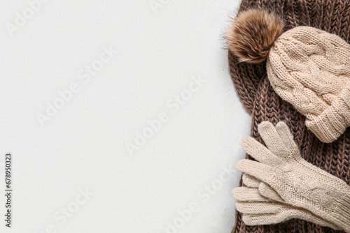 Knitted gloves with warm scarf and hat on white grunge background photo