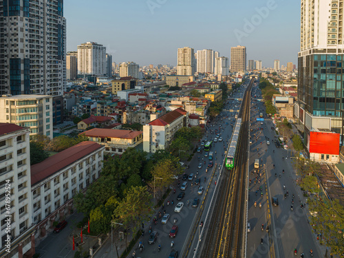 Hanoi skyline cityscape at sunset on Nguyen Trai street, with electrical train running on rails.