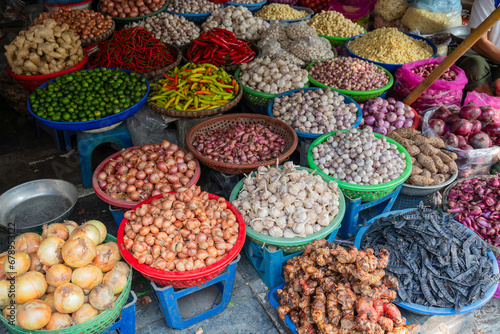 Baskets of different types of dried fruit, herbs, vegetables in an outdoor market on Hanoi street
