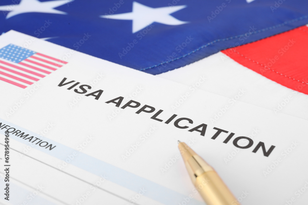 Immigration to USA. Visa application form and pen on flag, closeup