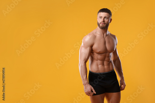 Young man is stylish black underwear on orange background. Space for text