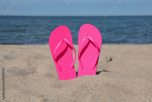 Stylish pink flip flops on beach sand