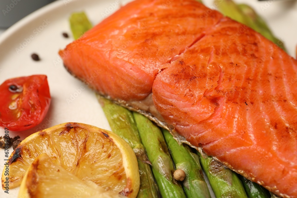 Tasty grilled salmon with asparagus, tomatoes and lemon on plate, closeup Tasty grilled salmon with asparagus, tomatoes and lemon on plate, closeup