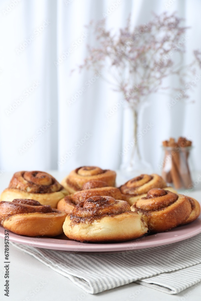 Many tasty cinnamon rolls on white table, closeup. Space for text