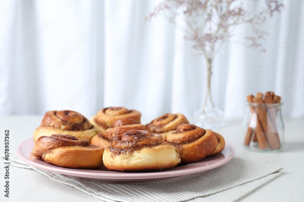 Many tasty cinnamon rolls on white table, space for text Many tasty cinnamon rolls on white table, space for text