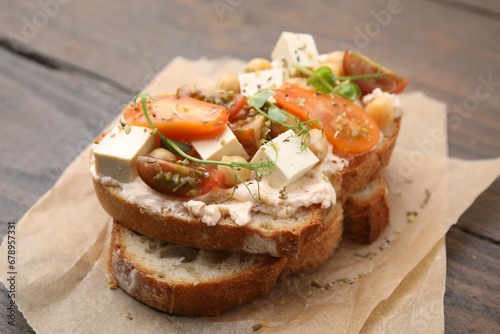 Tasty vegan sandwich with tomatoes, tofu and chickpeas on wooden table, closeup