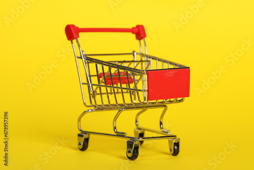 Small metal shopping cart on yellow background