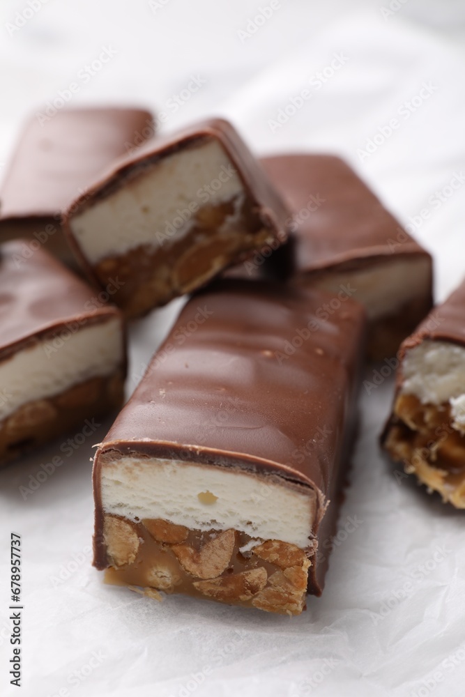 Tasty chocolate bars with nougat and nuts on white table, closeup