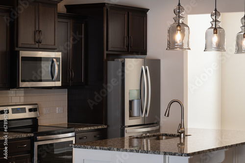 Modern townhouse kitchen with kitchen appliances and lighting fixtures. Investment, renting, or house ownership concept. photo