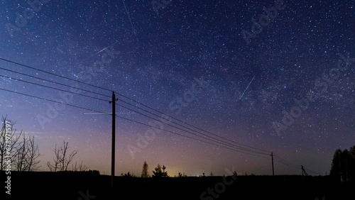 Natural Night Starry Sky. Starry sky with meteor trails and silhouettes of electric poles.