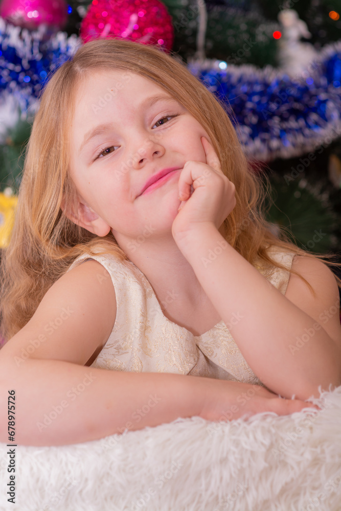 A beautiful elegant girl near the Christmas tree in the New Year. Holiday. New Year. The child is a model. A beautiful elegant girl near the Christmas tree in the New Year. Holiday. New Year. The child is a model.