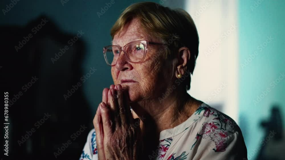 Faithful senior woman Praying at home with eyes closed. Hopeful Spiritual theme during old age Faithful senior woman Praying at home with eyes closed. Hopeful Spiritual theme during old age