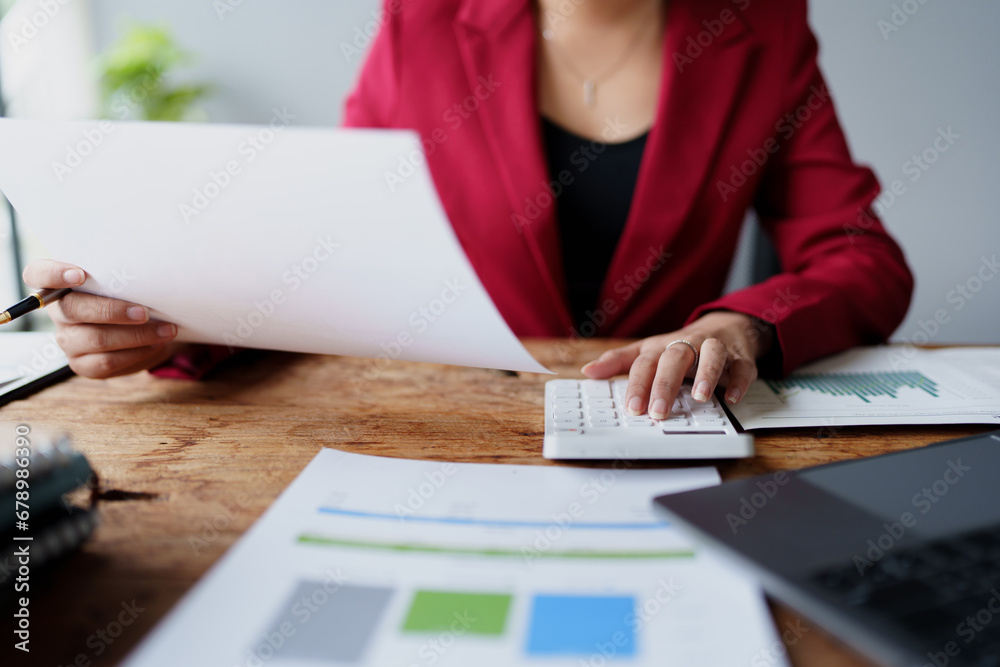 businesswoman or accountant working on calculator and laptop computer to calculate business data during using accountancy document at office businesswoman or accountant working on calculator and laptop computer to calculate business data during using accountancy document at office