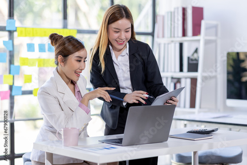 Team of confident asian business women point to graphs and charts to analyze market data, balance sheet, account, net profit to plan new sales strategies to increase production capacity. 