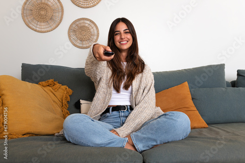 Happy caucasian woman watching TV sitting on the sofa relaxing.