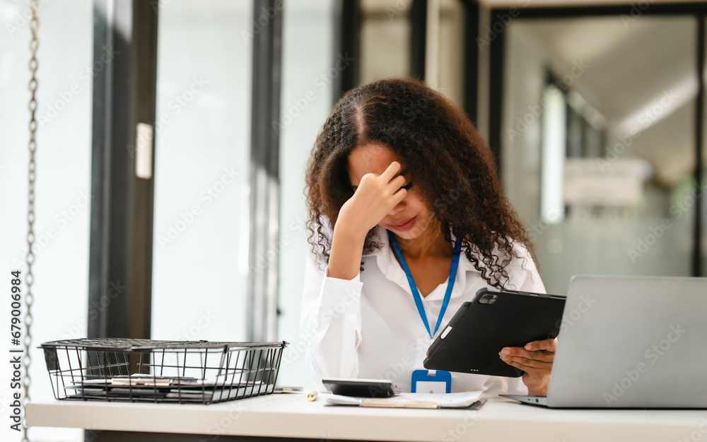 African American businesswoman at her desk, looking stressed and troubled, possibly over a challenging issue at work. African American businesswoman at her desk, looking stressed and troubled, possibly over a challenging issue at work.
