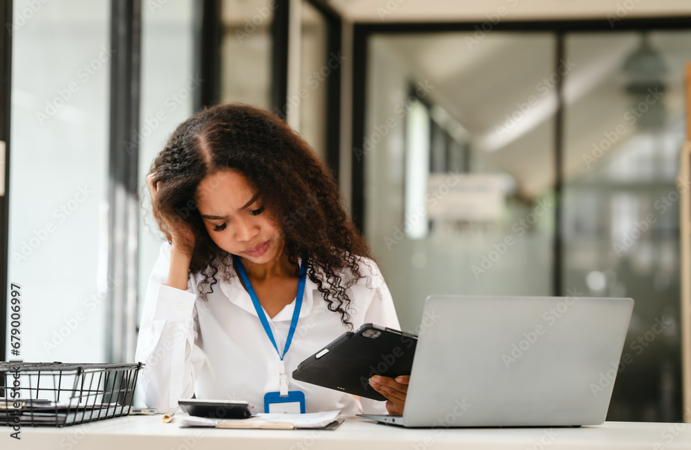 African American businesswoman at her desk, looking stressed and troubled, possibly over a challenging issue at work. African American businesswoman at her desk, looking stressed and troubled, possibly over a challenging issue at work.