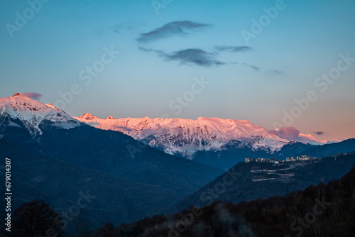 Sunlight cover the mountain peaks covered with snow. Scenic evening in the mountains