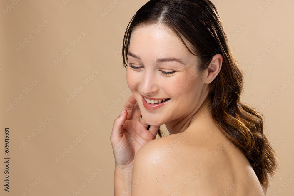 Caucasian woman with brown hair wearing natural makeup on beige background, copy space Caucasian woman with brown hair wearing natural makeup on beige background, copy space