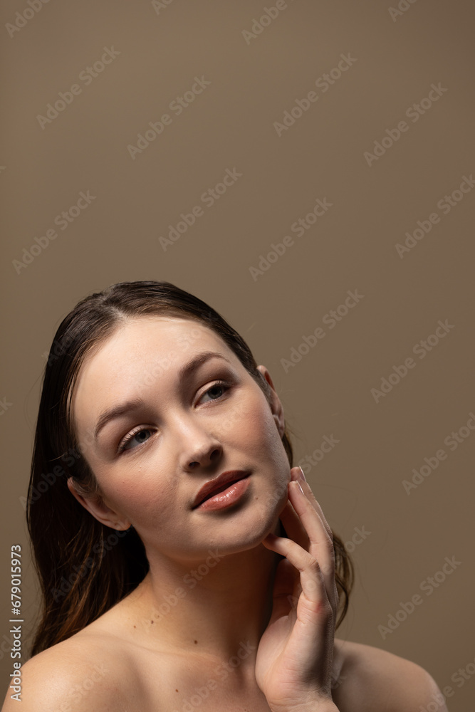 Caucasian woman with brown hair wearing natural makeup on beige background, copy space Caucasian woman with brown hair wearing natural makeup on beige background, copy space