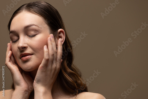 Caucasian woman with brown hair wearing natural makeup on beige background, copy space