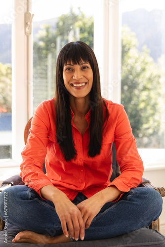 Free Download Happy biracial woman having video call sitting cross legged smiling in sunny room - GFXLoad