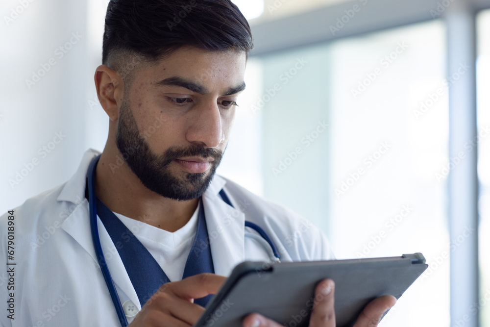 Biracial male doctor using tablet in sunny hospital room Biracial male doctor using tablet in sunny hospital room