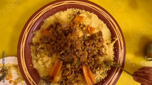 A traditional Arabic Friday lunch as intergenerational hands gather around a big couscous plate filled with flavorful meat and vegetable couscous, a festive dish rich in herbs and spices. photo