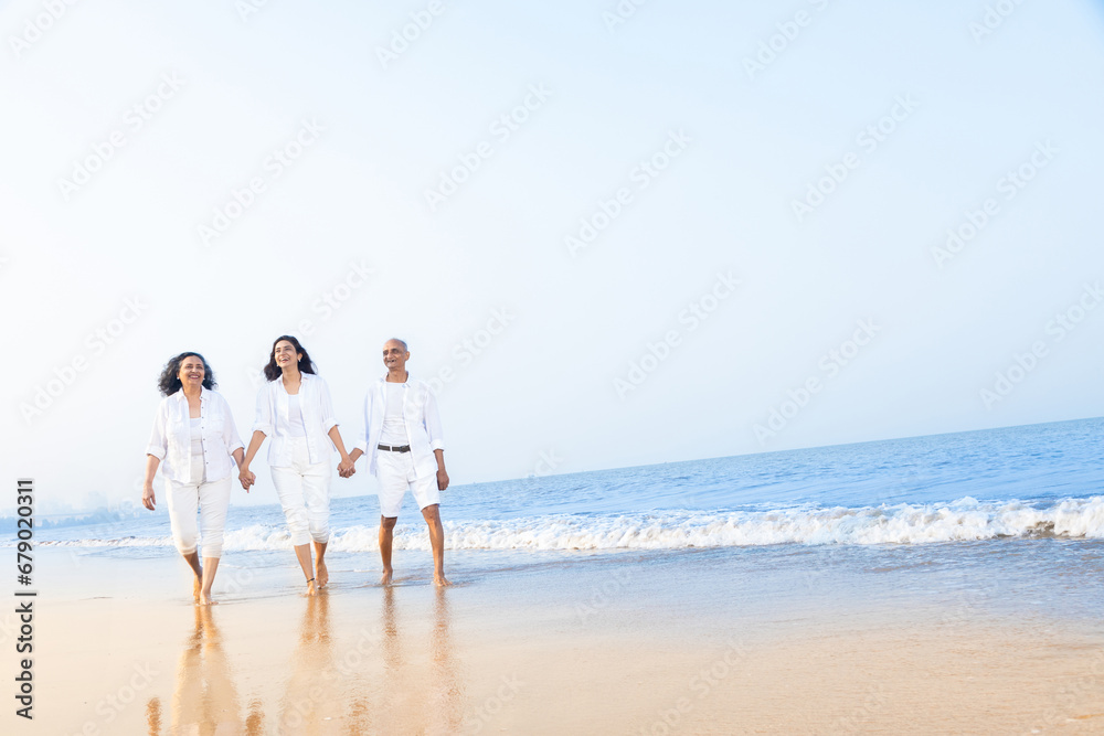 Happy senior indian couple with beautiful young daughter enjoying vacation at beach. Copy space