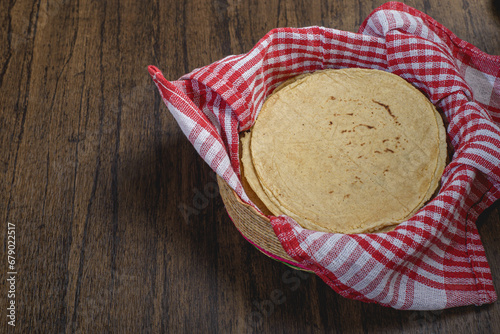 Tortillas in a woven basket on a wooden table. Typical mexican food.