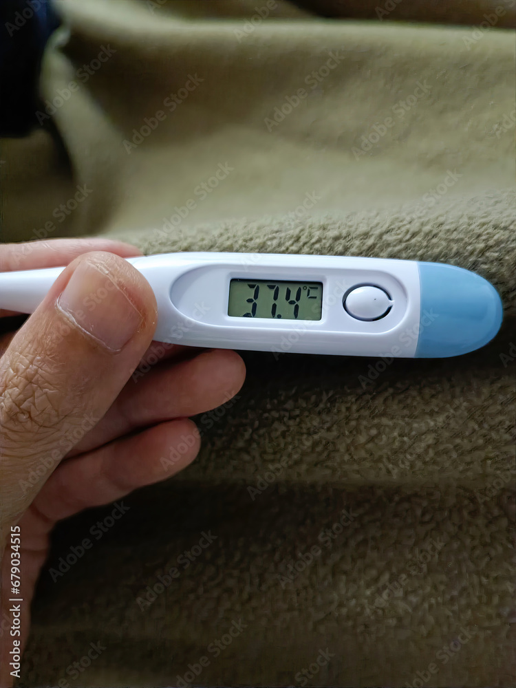 Hand holding digital thermometer on blue background Hand holding digital thermometer on blue background