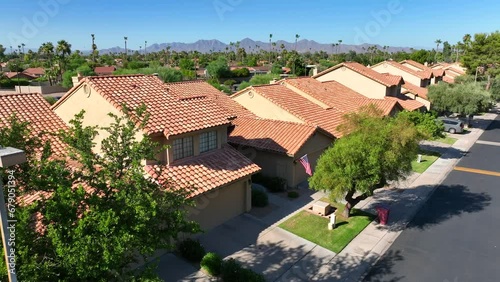 Southwest USA neighborhood Aerial view of terracotta roof homes, green trees, with mountains in the background.