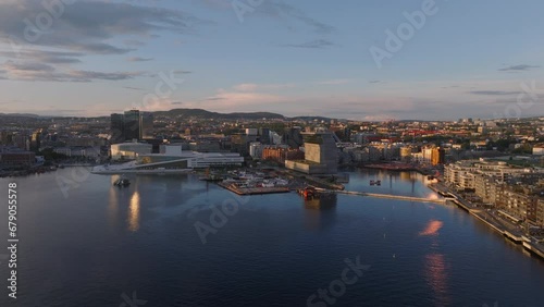 Amazing picturesque aerial view of bay in city at golden hour. Buildings on waterfront lit by low sun. Munch museum and Oslo Opera House. Oslo, Norway