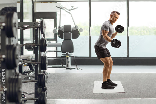Young fit man lifting dumbbells at a gym