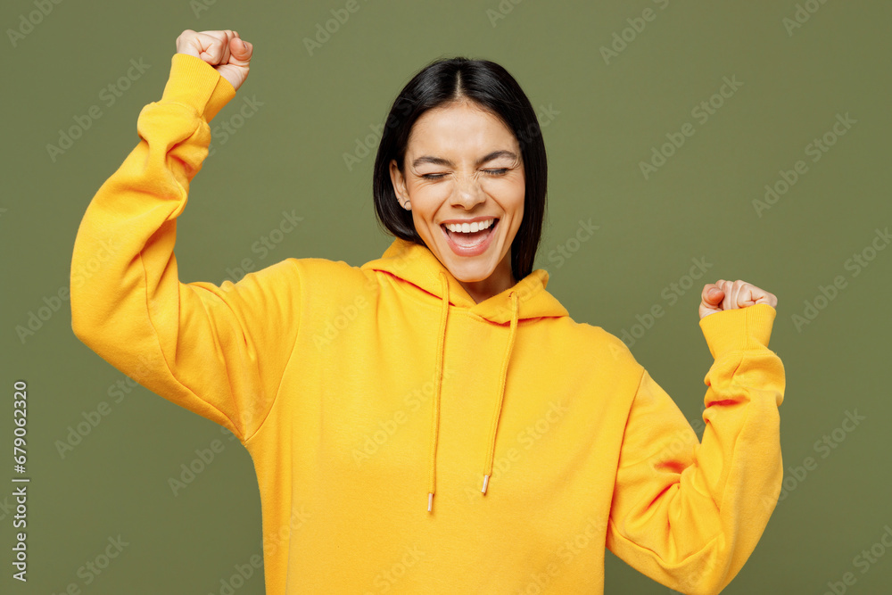 Φωτογραφία Young overjoyed excited happy fun Latin woman wearing yellow hoody casual clothes doing winner gesture clench fist say yes isolated on plain pastel green background studio portrait