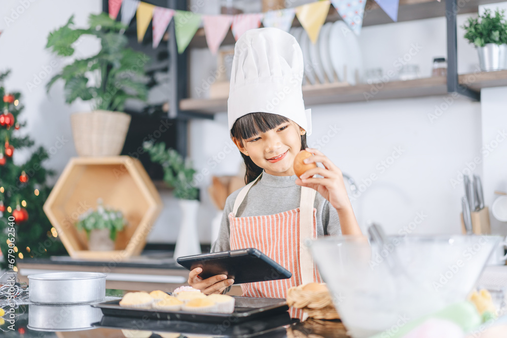 Little asian girl with chef hat and apron cooking at home kitchen Little asian girl with chef hat and apron cooking at home kitchen