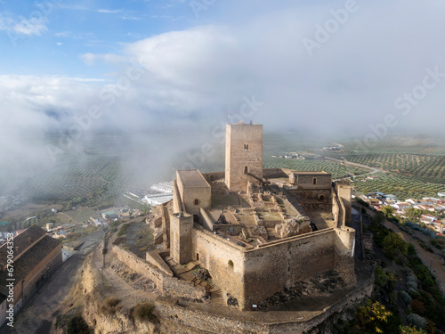 el hermoso castillo de Alcaudete rodeado por un banco de niebla, Andalucía	 photo