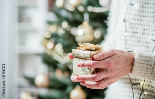 hand holding Christmas gift box in front of holiday lights