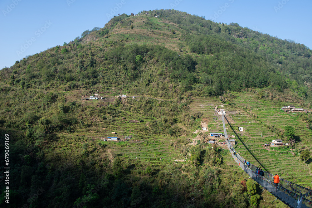 Naklejka premium Group of tourist crossing the river by the suspension bridge nearly Jhinu Danda village in Nepal.