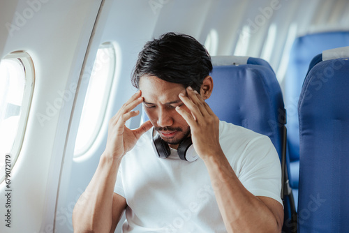 headache on airplane Male passenger is afraid and feels bad while flying on an airplane. photo
