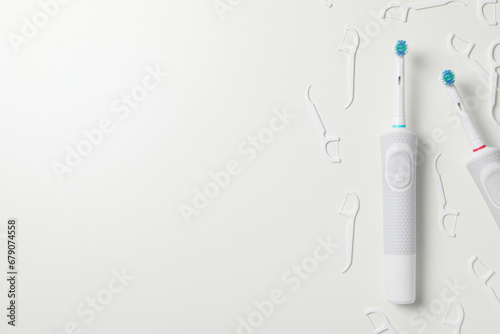 Electric toothbrushes and dental floss on white background, space for text