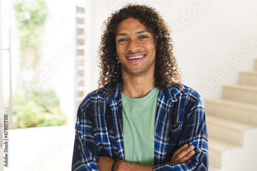 Happy biracial man with long dark curly hair laughing in sunny living room at home photo
