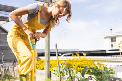 Happy blonde caucasian woman working in sunny garden