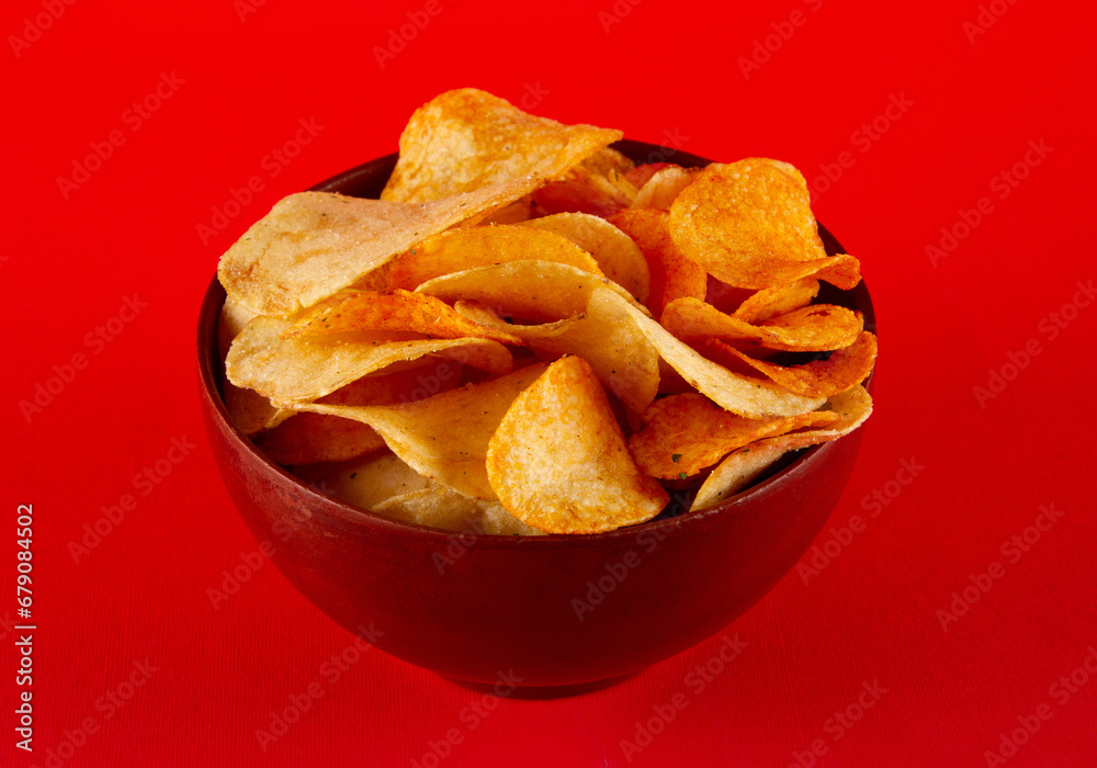 Potato chips in clay bowl isolated on red background. side view Potato chips in clay bowl isolated on red background. side view