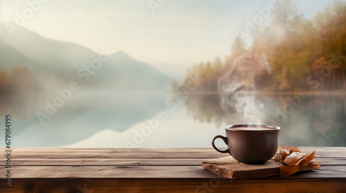 Cup of coffee on wooden table in front of foggy lake