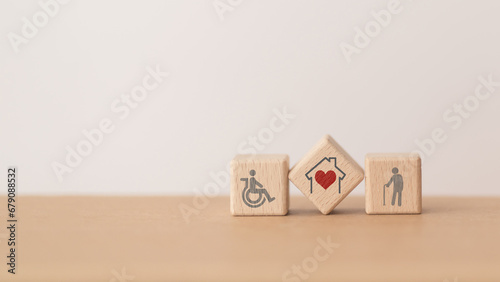 house with red heart  inside  wooden cube block and elderly and disability person icon, including copy space, for home or nursing care for aging people concept photo
