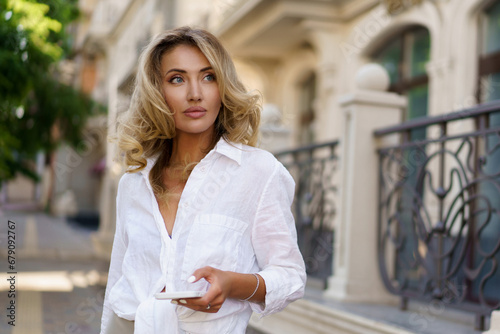 Outdoor portrait of beautiful  blond woman  perfect wavy hairs  holding luxury hand bag. Fashion acsessories , Casual outfit. © Svetlana Sokolova